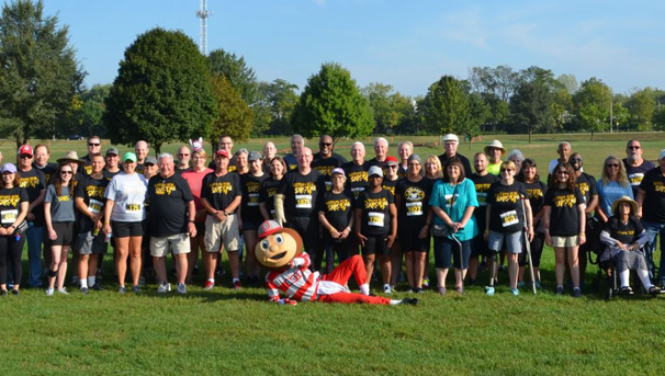Brutus Buckeye poses on the ground in front of a large group of people