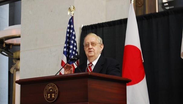 Brad Richardson standing at a wooden podium, speaking into a microphone