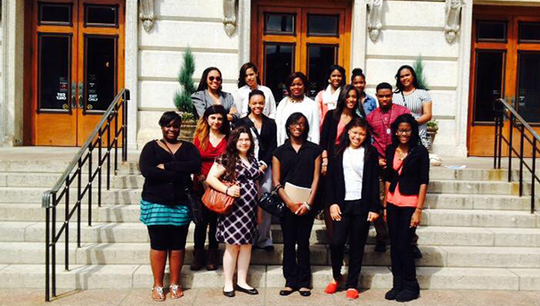 Group of students standing outside on steps smiling for a photo