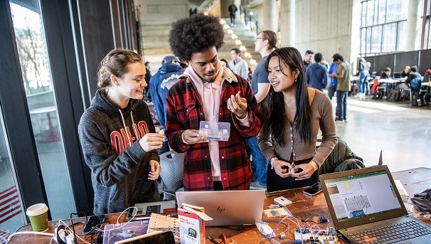 Three students over looking computer parts
