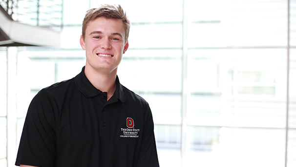 Individual smiling for a photo with windows in the background