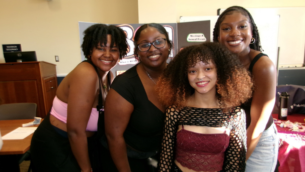 Group of four students standing in front of BSA poster