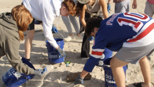 Students working together to clean up trash on the beach