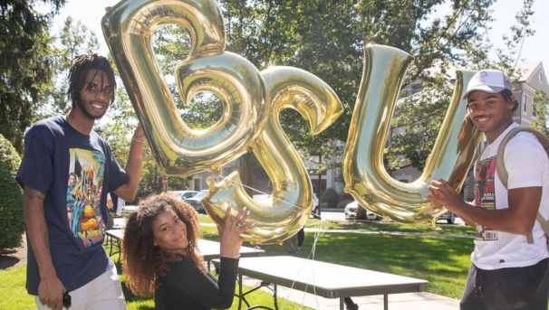 Three students posing with BSU balloons at a past event