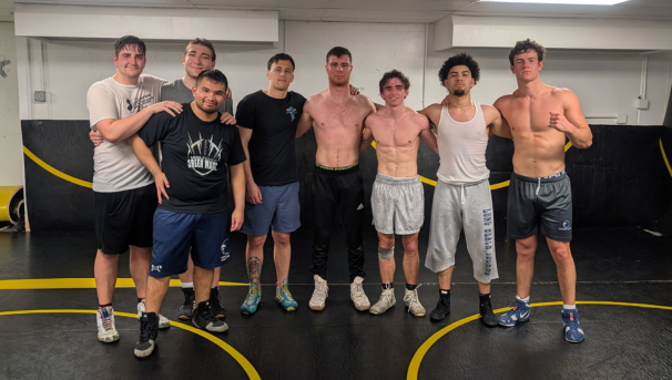 Group of wrestlers posing for a photo in their practice area