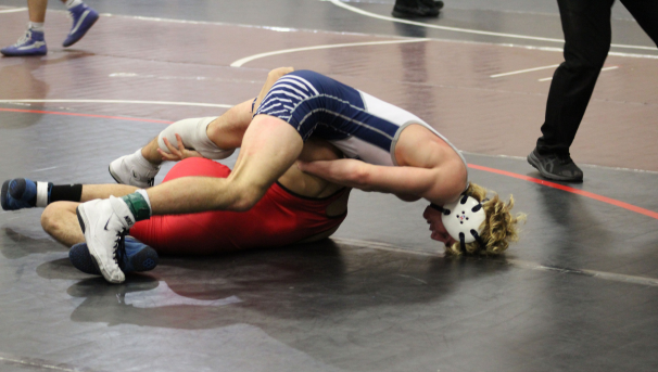 Monmouth wrestler on a mat with an opponent