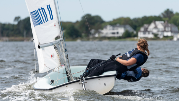 Two students on the water pulling on their sails