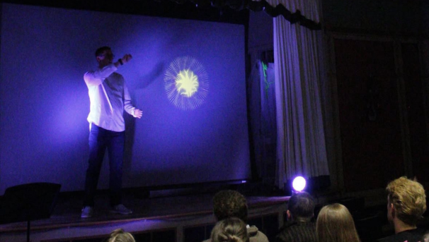 student performing on a dark stage with purple lights