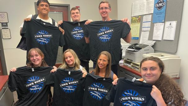 Students holding up commworks tshirts