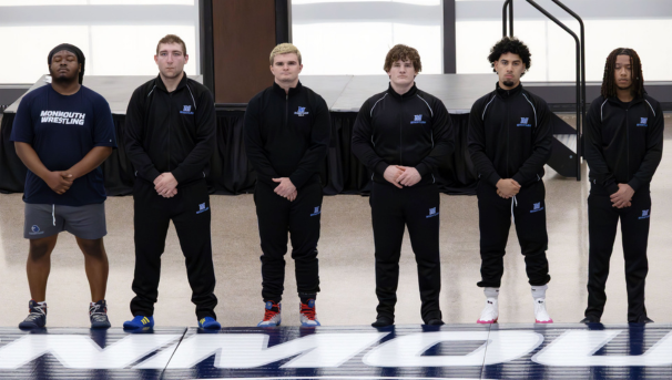 posed group photo of 6 wrestlers all in matching post-match outfits