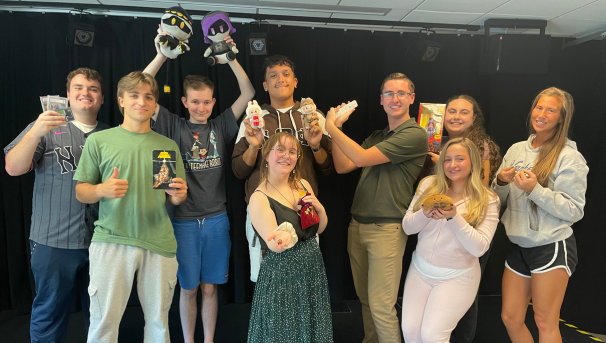 Commworks students holding props in a classroom