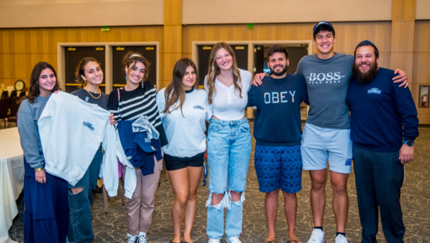 students smiling for a group photo, some holding Chabad-branded gear