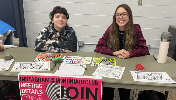 two club members tabling at an involvement fair with poster and coloring sheets
