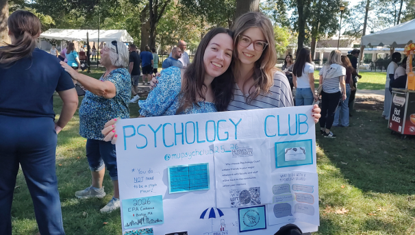 two female students at involvement fair with poster