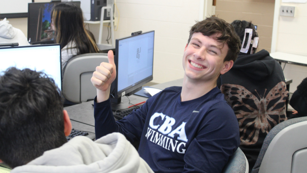 male member smiling and thumbs up at a computer