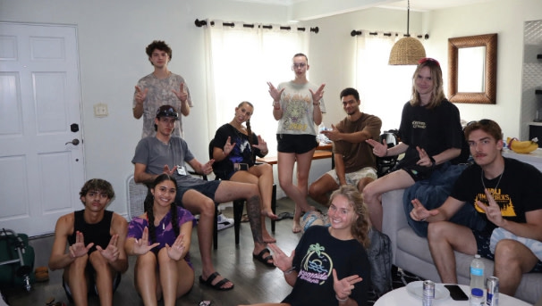 Members in San Diego, in Fall 2025, holding up the NAU jacks sign in their AirBnB.