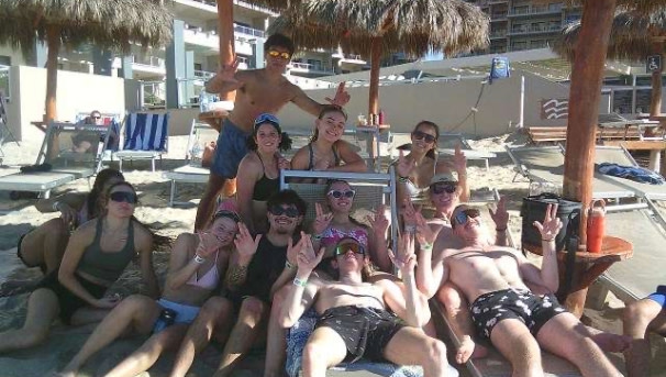 Members from Fall 2024 holding up the NAU jacks sign on the beach of Mexico.