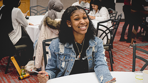 Student sitting at a table smiling for a photo