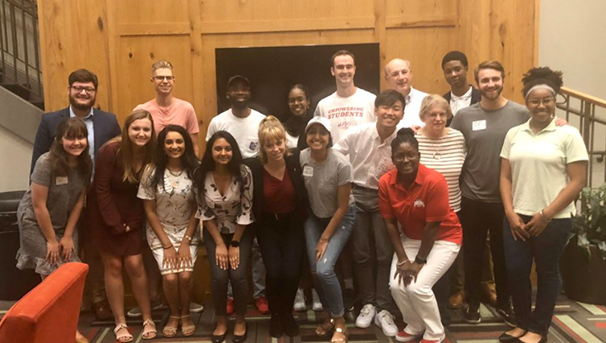 A large group in the Ohio Union's KBK lounge's fireplace, smiling towards the camera