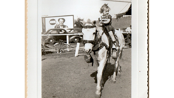 Child riding a pony in a black and white image