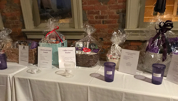 Various raffle baskets on a table. There are clear and purple cups to put the raffle tickets in