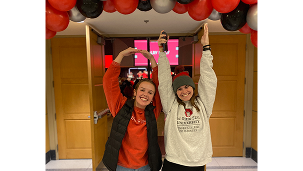 Two individuals smiling for a photo with their arms held up for O-H