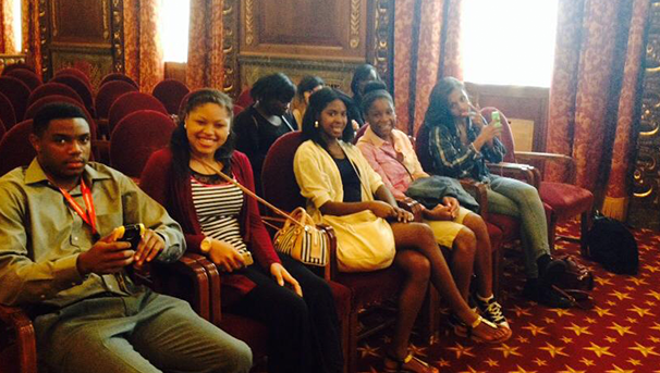 Group of students smiling for a photo inside a building sitting in chairs