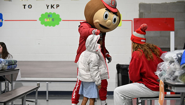 Brutus standing next to child in a school cafeteria with other people