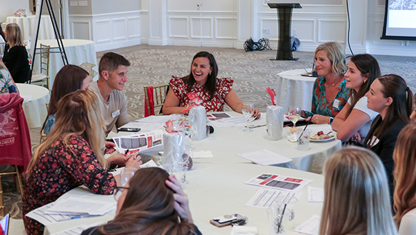 Group of individuals sitting around a table laughing and talking at an event