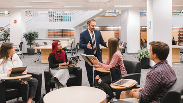 Students sitting at a table talking to a professor
