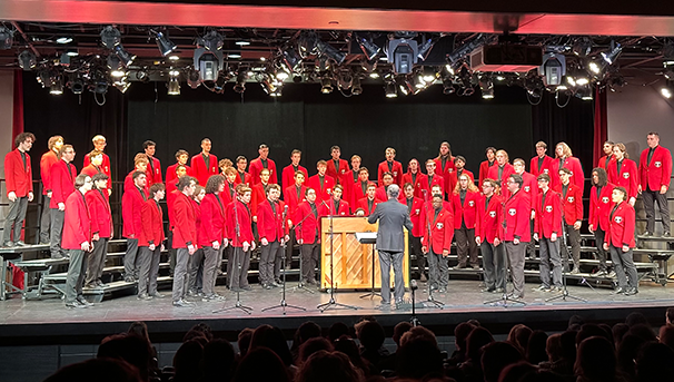 Men's Glee Club members standing on stage singing at a concert