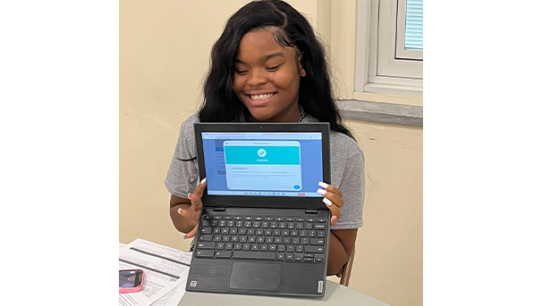 Student holding laptop smiling