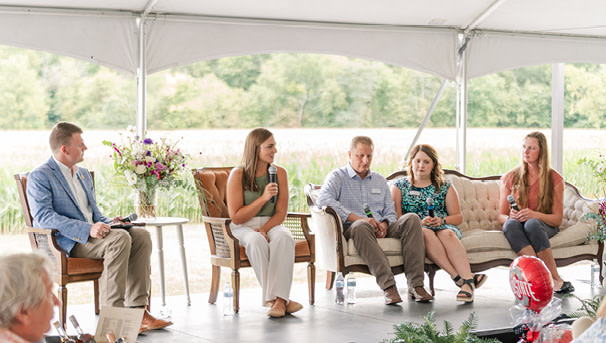 Five panelists on cozy outdoor stage