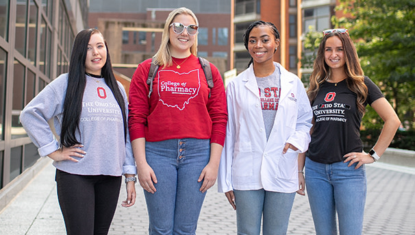 Four pharmaceutical students pose for a picture on a grey brick road