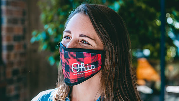 A girl with a plaid Script Ohio mask looking past the camera
