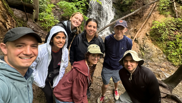 Group posing outside with waterfall