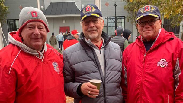 Three individuals standing together smiling for a photo