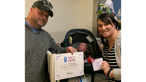 A mother and father taking home their baby from the NICU