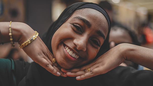 Individual smiling for a photo while holding their hands under their chin