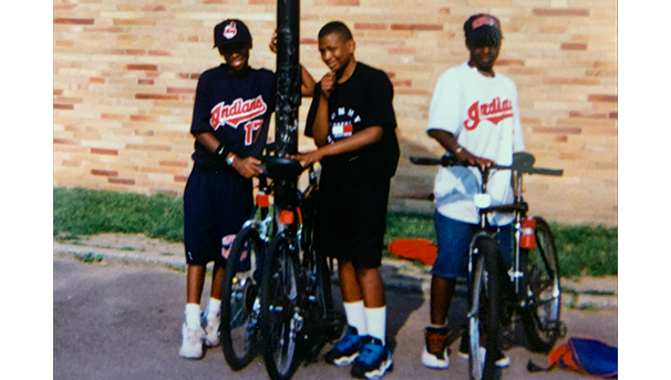 Three individuals standing next to their bikes outside smiling for a photo