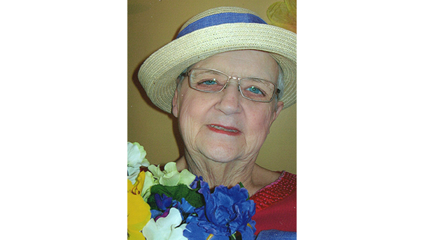 Individual smiling while wearing a hat and holding flowers