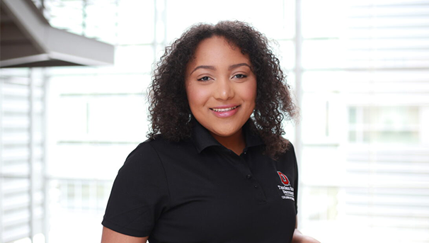 Individual smiling for a photo with windows in the background