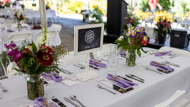 Flowers in vases on a tablecloth with purple cancer ribbon napkins and silverware