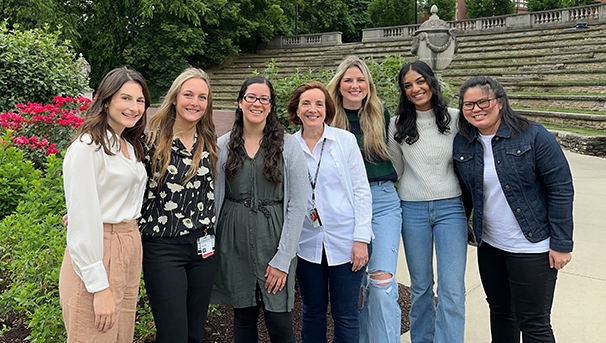 Group of individuals standing outside smiling for a photo