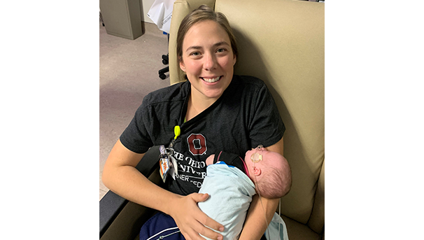 NICU nurse holding baby in arms while sitting in a chair