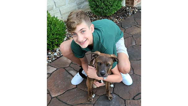 Carter squatting outside his house to hug his puppy