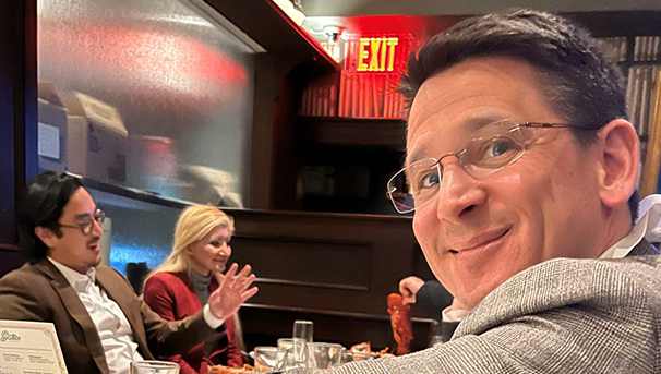 Alumni sitting and eating at a long table