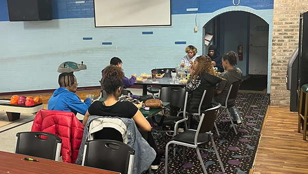 Students sitting at tables in bowling alley