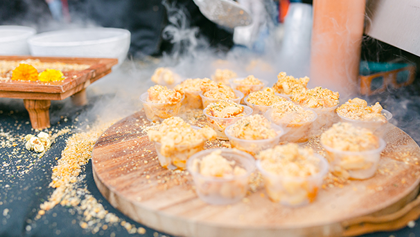 Small cups of macaroni and cheese sitting on a wooden tray