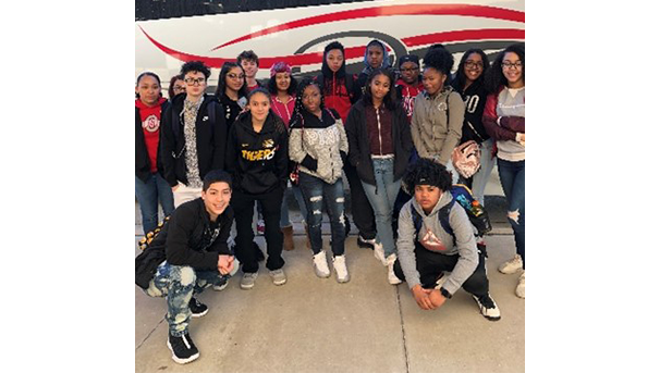 Group of students standing outside in front of a bus for a photo